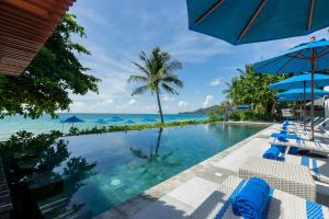 a swimming pool with chairs and a view of the ocean at Synergy Samui in Chaweng