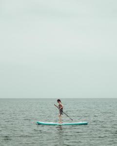 una mujer en una tabla de surf de remo en el océano en Akti Apollona en Apollon