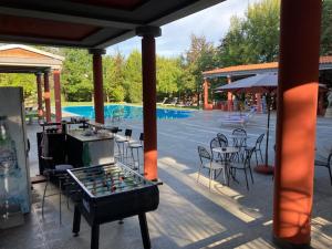 eine Tischtennisplatte auf einer Terrasse mit Stühlen und einem Pool in der Unterkunft Ex Villa Gastaldi in Asti