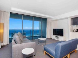 a living room with a couch and a television at LUXURY APARTMENT- with WATER VIEWS FROM EVERY DIRECTION in Gold Coast