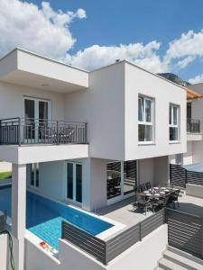 a white house with a swimming pool and a patio at Villa Dorso with heated pool in Klis