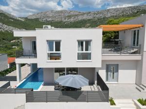a large white house with a swimming pool at Villa Dorso with heated pool in Klis