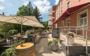 eine Terrasse mit Tischen, Stühlen und einem Sonnenschirm in der Unterkunft Hotel Oranien Wiesbaden in Wiesbaden