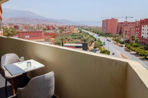 een tafel en stoelen op een balkon met uitzicht op de stad bij Hotel SunSet Beni Mellal in Beni Mellal