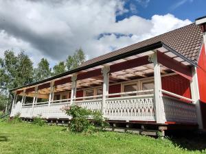 - un grand bâtiment rouge avec une terrasse couverte blanche dans l'établissement Villa Stolle, à Hammarstrand