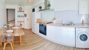 a white kitchen with a table and a sink at Thuir, Charmante Maison T2 Climatisée in Thuir