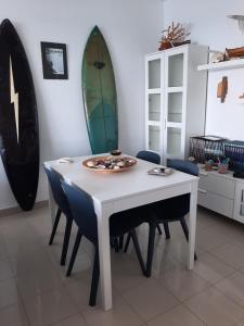 une table blanche avec des chaises et une planche de surf sur le mur dans l'établissement Laluna, à La Laguna