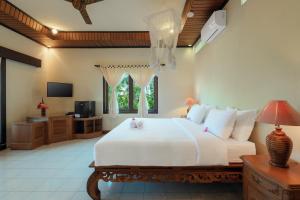 a bedroom with a large white bed and a television at Banyualit Spa 'n Resort Lovina in Lovina