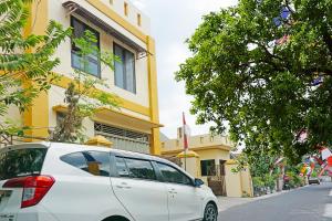 a white car parked in front of a yellow building at OYO 91580 Kost Bougenville Syariah in Madiun