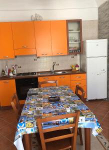 a kitchen with a table with orange cabinets and a white refrigerator at La casa di Andrea in Favignana