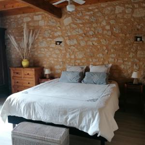 1 dormitorio con cama y pared de piedra en Le Marronnier, en Saint-Vincent-de-Pertignas