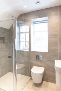 a bathroom with a toilet and a shower and a window at Hampden Apartments - The William in Eton