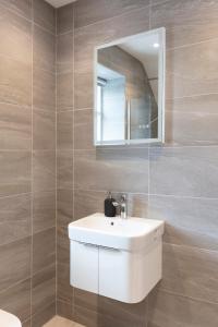 een badkamer met een witte wastafel en een spiegel bij Hampden Apartments - The William in Eton
