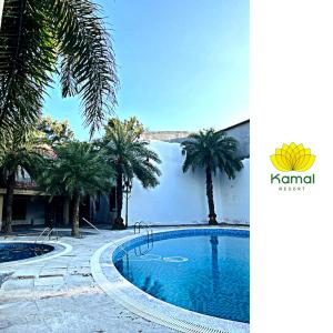 a swimming pool with palm trees in front of a building at Kamal Resorts - The Luxury Of Being Yourself in Ludhiana