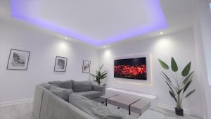 a living room with a couch and a tv on the wall at Stunning Luxury Apartment Near Motherwell in Wishaw