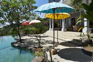 ein Haus mit 2 Sonnenschirmen und einem Pool in der Unterkunft Villa Reva Bali in Temukus