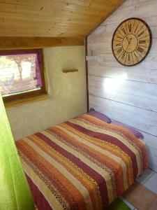 Bett in einem Zimmer mit einer Uhr an der Wand in der Unterkunft maisonnette écologique isolée en botte de paille in Ploërmel