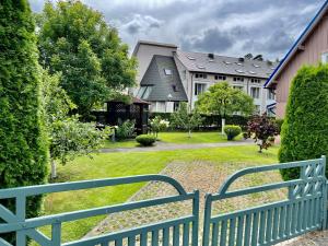 a green fence in front of a yard with houses at Gedimino Apartamentai in Juodkrantė