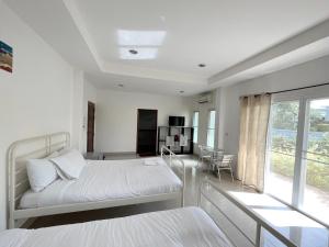 a white bedroom with two beds and a window at Home JANO in Cha Am