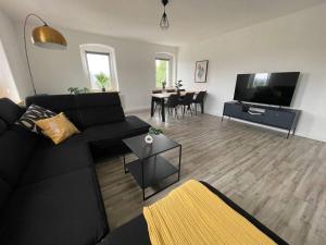 a living room with a black couch and a flat screen tv at Modern 4 Zi Rooms Netflix, Wifi, Parken CasaLuna85 in Flöha