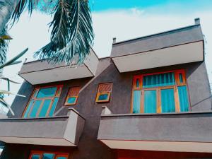 a building with red and blue windows and a palm tree at Ridmi Home Stay in Karagampitiya