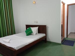 1 dormitorio con 1 cama con cortina verde en Ridmi Home Stay, en Karagampitiya