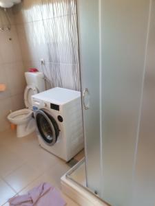 een badkamer met een wasmachine en een toilet bij Impeccable 2-Bed House in Privlaka Croatia in Privlaka