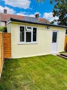 ein kleines gelbes Haus mit einem Rasenplatz in der Unterkunft Superb and Comfortable 3BD Home in Dagenham in Dagenham