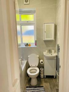 a bathroom with a toilet and a sink and a window at Superb and Comfortable 3BD Home in Dagenham in Dagenham
