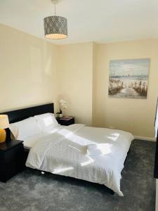 een slaapkamer met een wit bed en een schilderij aan de muur bij Superb and Comfortable 3BD Home in Dagenham in Dagenham