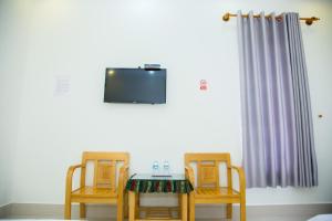 two chairs and a table with a television on a wall at Sài Gòn Phan Rang Hotel in Thôn Mỹ Phước