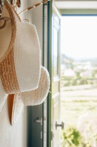 un chapeau de paille suspendu à côté d'une fenêtre dans l'établissement Just Like Home - Casa Antonio em Paredes de Coura, à Paredes de Coura