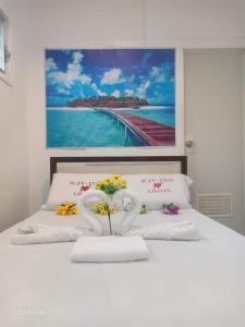un letto bianco con due cigni e fiori sopra di WJV INN LILOAN a Liloan