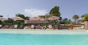 a swimming pool with chairs and umbrellas at RoccaSeta in Scicli