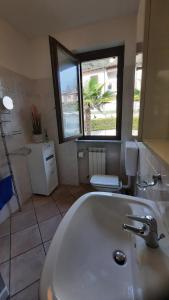 baño con lavabo blanco grande y 2 ventanas en Residenza La Rocca, en Castello Valsolda