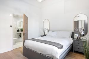 a white bedroom with a large bed and mirrors at Luxury Majestic Apartment in Marylebone in London