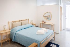 Schlafzimmer mit einem Bett mit blauer Bettwäsche und einem Spiegel in der Unterkunft Palamì - Polignano a Mare Holiday House in Polignano a Mare