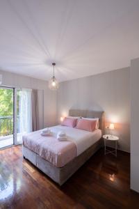 una camera bianca con un grande letto con cuscini rosa di Chania Central Apartment a Chania