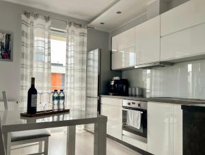 a kitchen with white cabinets and a table with a bottle of wine at Przestronne Studio Blisko Morza in Gdańsk