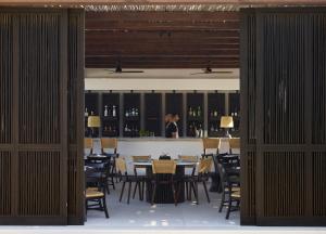 a person standing in a restaurant with tables and chairs at Kalesma Mykonos in Ornos