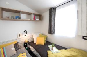 Cette petite chambre comprend un lit et une fenêtre. dans l'établissement Camping Le Suroit, au Bois-Plage-en-Ré