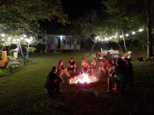 un grupo de personas sentadas alrededor de una fogata por la noche en Sveri Adventure Camp, en Chiatʼura