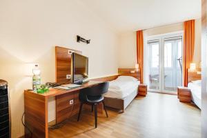 ザルツブルクにあるホテル アストリアのデスクとベッドが備わるホテルルームです。