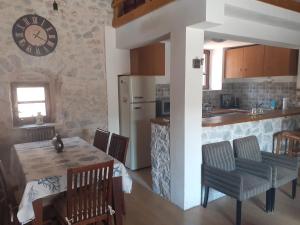 een keuken met een tafel en een klok aan de muur bij Tsitalia cottage house in Leonidion