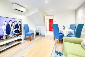 a living room with a large tv and blue chairs at 2 bedroom luxury House in Oxford in Oxford