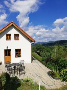 Cette maison blanche dispose d'une terrasse avec une table et des chaises. dans l'établissement charming house with beautiful landscape, à Frýdštejn