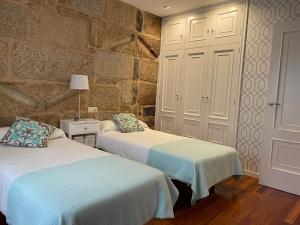 a bedroom with two beds and a stone wall at Sweet Home Pontevedra in Pontevedra