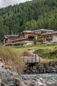 a bridge over a river in front of a building at 4 Sterne Superior Mühle Resort 1900 - Adults only in Obergurgl