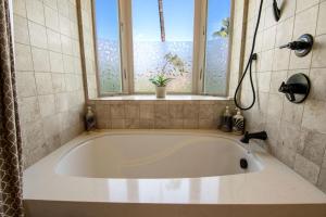 a bath tub in a bathroom with a window at Villa Moana Maui in Kihei