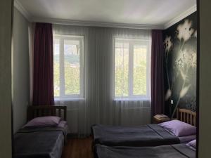 1 Schlafzimmer mit 2 Betten und 2 Fenstern in der Unterkunft Guest House Demma in Kazbegi